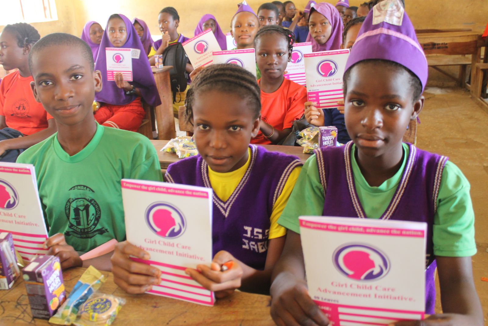 Students holding GCCAI exercise books during a school outreach